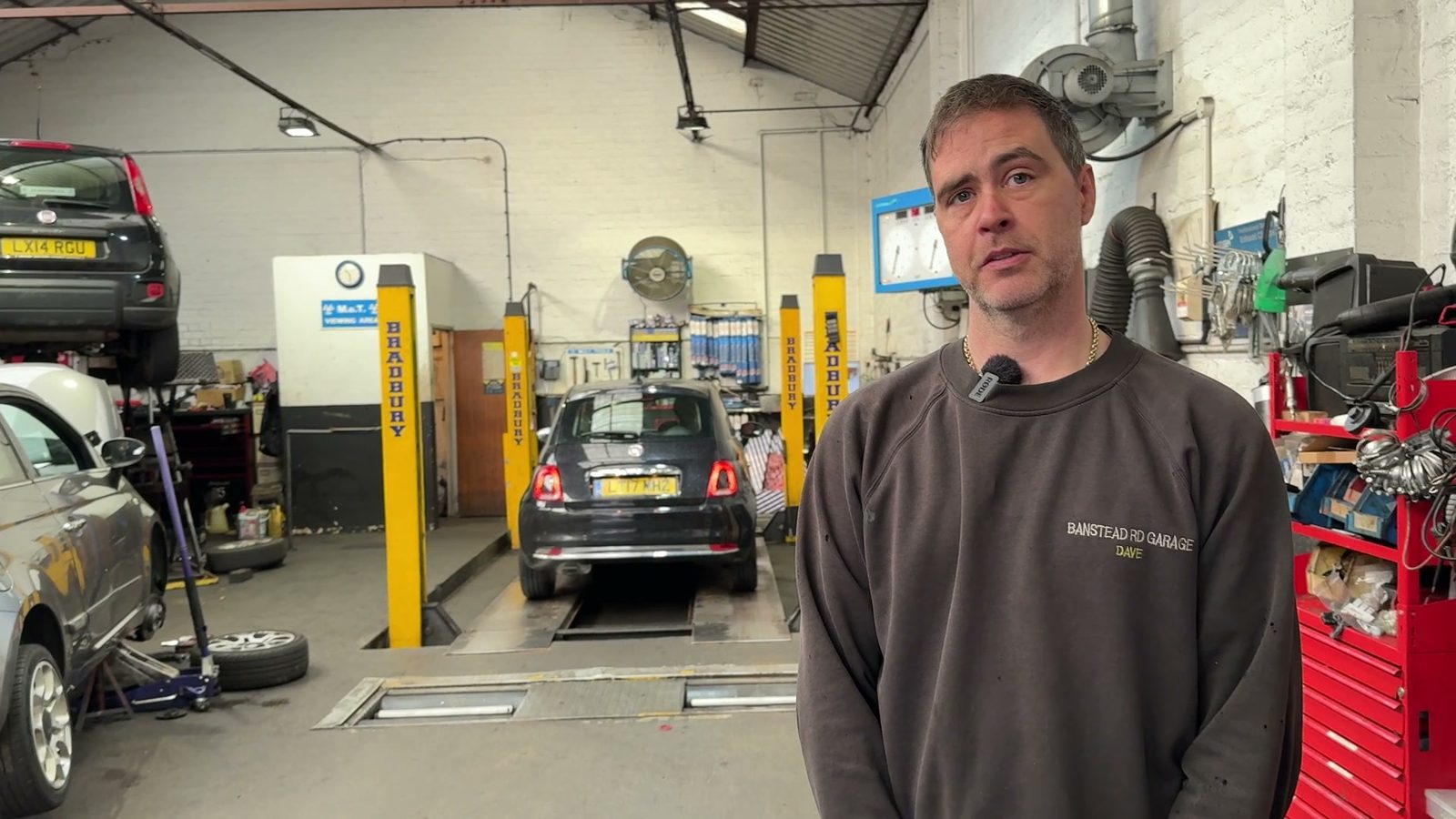 Dave in the workshop during the recorded interview, 6 November 2025, with the MOT test bay behind him.
