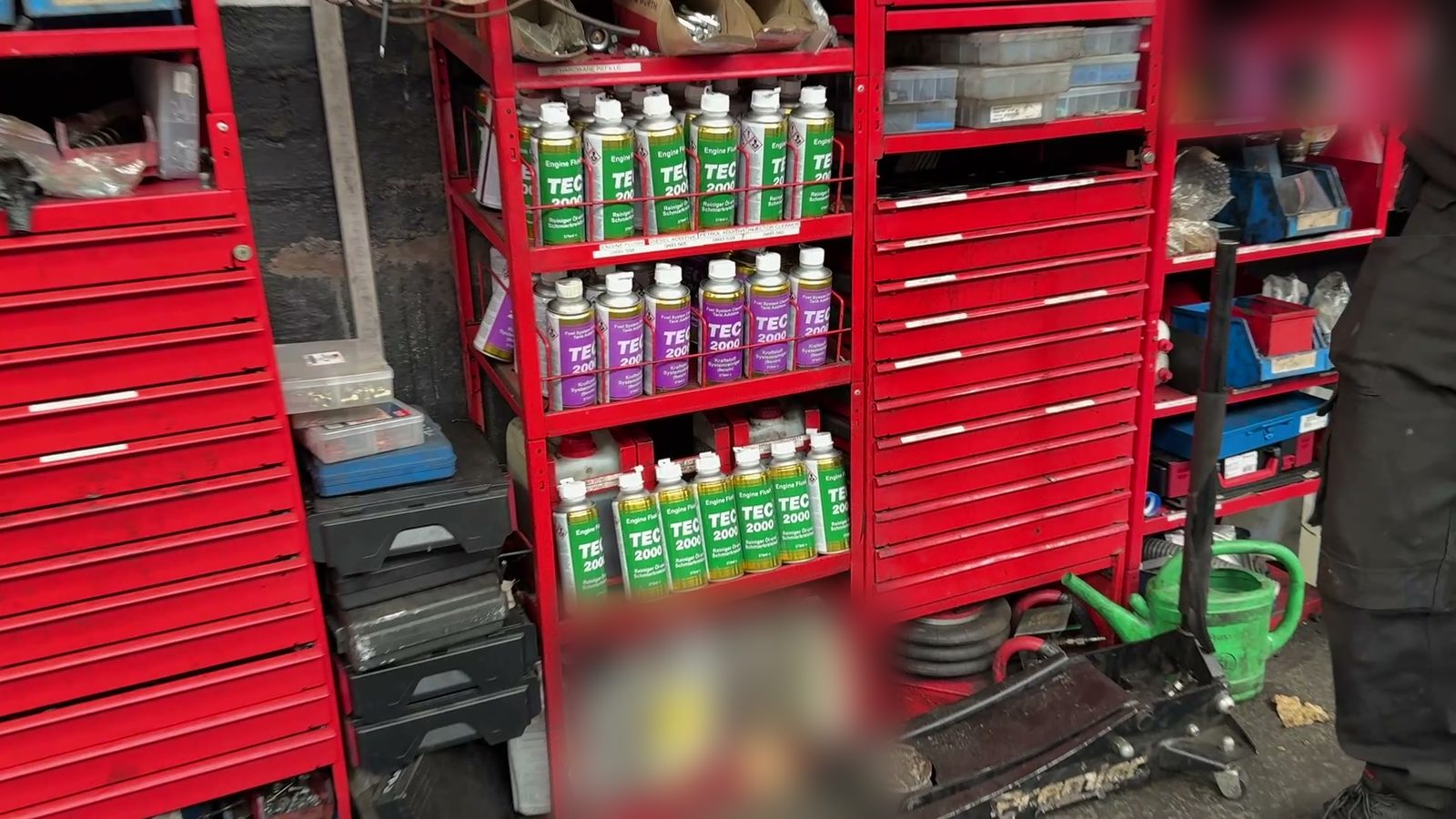 The TEC 2000 rack built into the side of a tool chest: Engine Flush (green cans) and Fuel System Cleaner for petrol engines (purple cans).