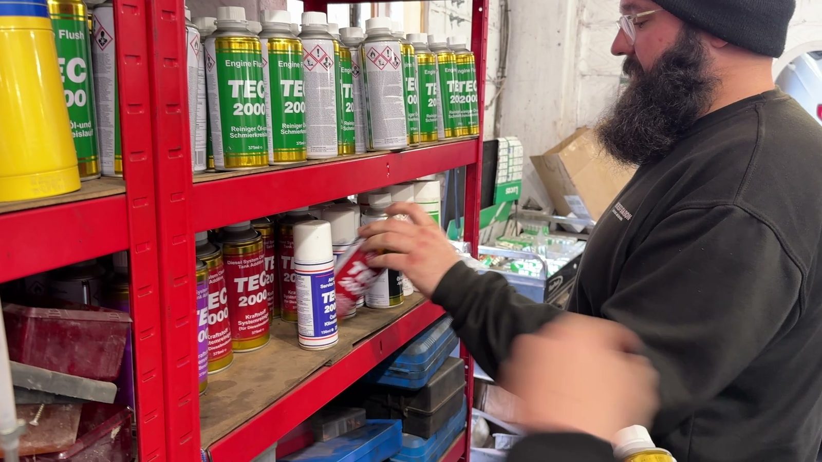 Ricky at the TEC 2000 shelf in the workshop: Engine Flush on the upper shelf, Diesel System Cleaner below.